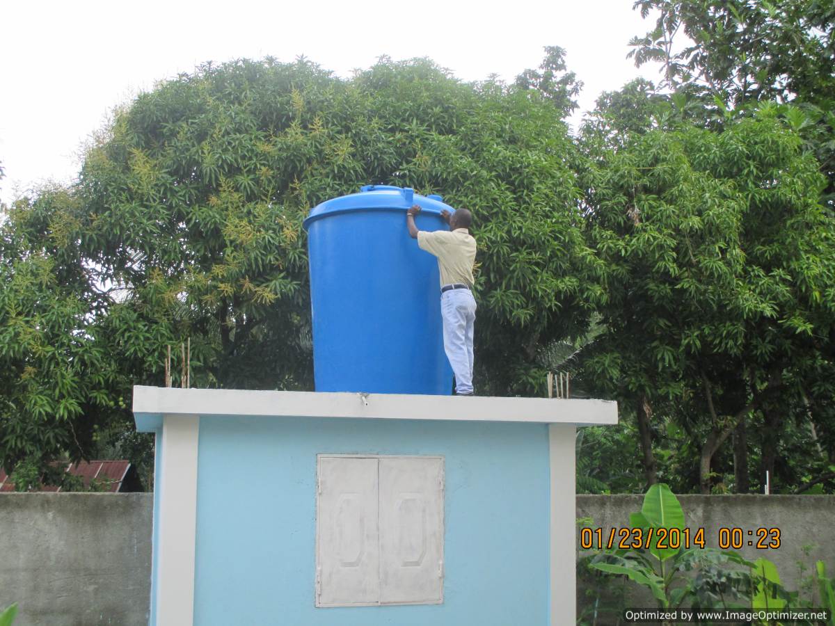 Man on top of building with rain barrel