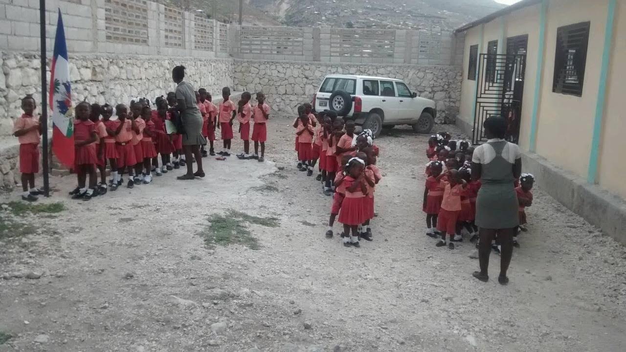 Group of school children in red uniforms standing outside school