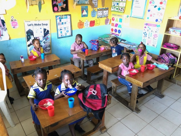Group of school children eating at desks