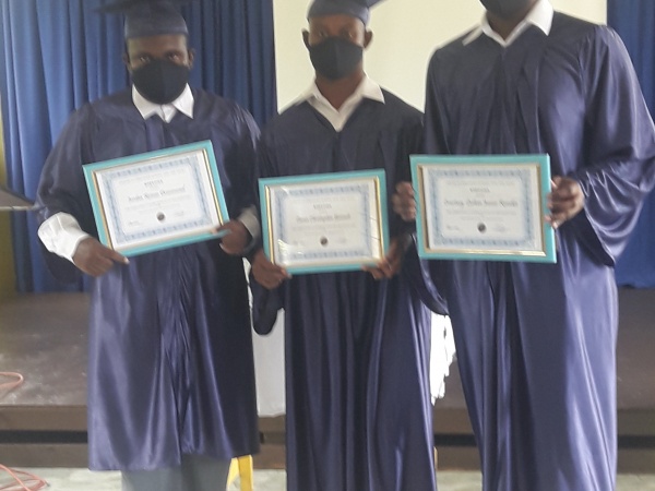 Three graduates holding diplomas