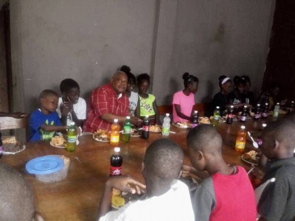 Man with group of children eating a meal at a table